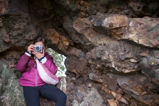 Child girl taking pictures from rock shelter. Children discover nature through the photography