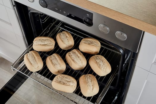 From above raw half baked bread buns on metal rack glide rack in oven