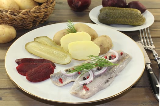 a plate of matjes fillet,peel potatoes,beetroot and sour cucumbers