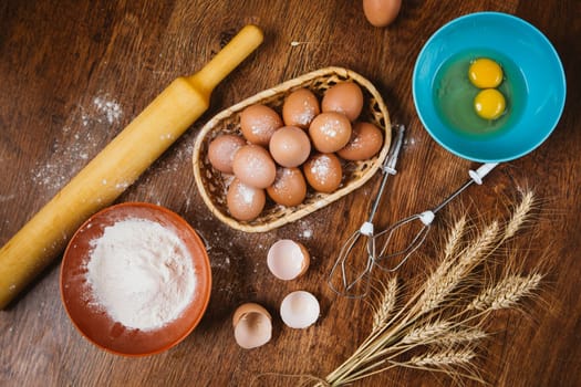 Baking cake in rural kitchen - dough recipe ingredients (eggs, flour, sugar) on vintage wooden table from above.