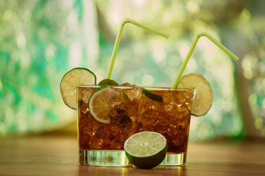 drink concept - cocktail with cola ice cubes and lime