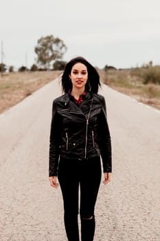 Brunette woman with black leather jacket in a lonely road