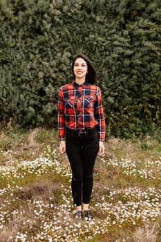 Pretty brunette girl with red plaid shirt in the park