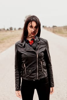 Brunette woman with black leather jacket in a lonely road