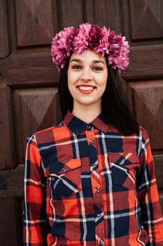Pretty stylish girl with pink flower crown and red plaid shirt In front of a wooden door