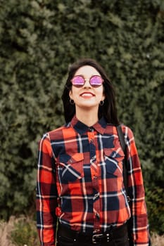 Pretty brunette girl with red plaid shirt in the park
