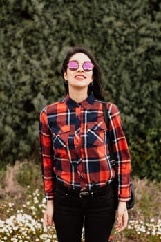 Pretty brunette girl with red plaid shirt in the park