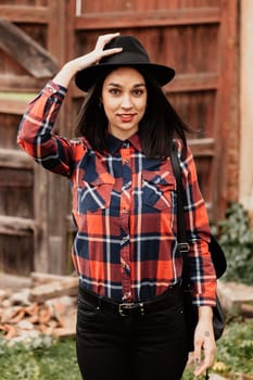 Pretty brunette girl with red plaid shirt and black hat