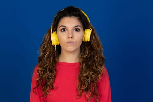 Portrait of beautiful caucasian girl with curly hair and headphones listening music isolated on a white background