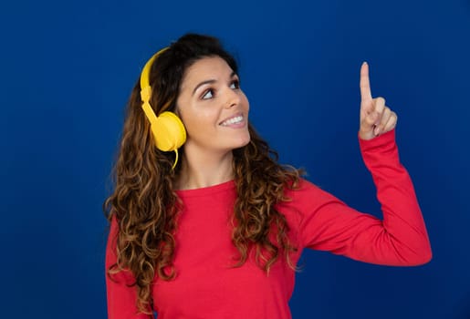 Portrait of beautiful caucasian girl with curly hair and headphones listening music isolated on a white background