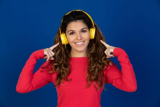 Portrait of beautiful caucasian girl with curly hair and headphones listening music isolated on a white background