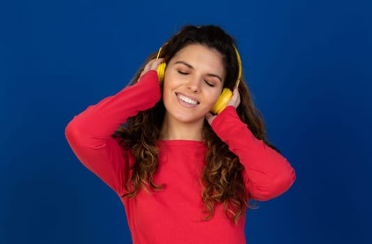 Portrait of beautiful caucasian girl with curly hair and headphones listening music isolated on a white background