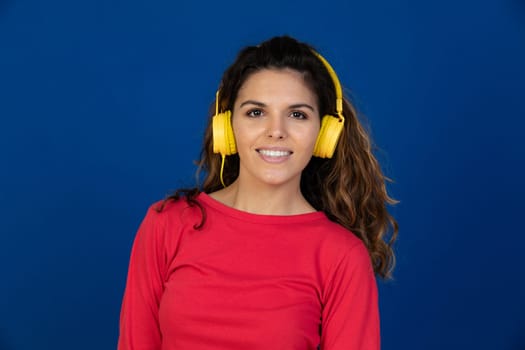 Portrait of beautiful caucasian girl with curly hair and headphones listening music isolated on a white background