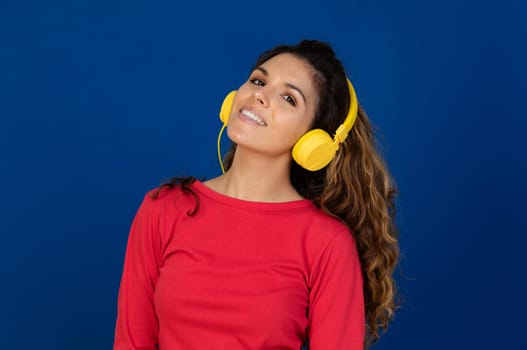 Portrait of beautiful caucasian girl with curly hair and headphones listening music isolated on a white background