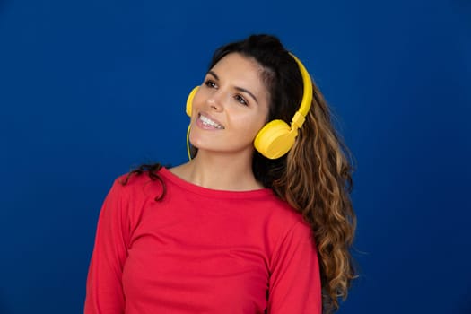 Portrait of beautiful caucasian girl with curly hair and headphones listening music isolated on a white background