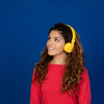 Portrait of beautiful caucasian girl with curly hair and headphones listening music isolated on a white background