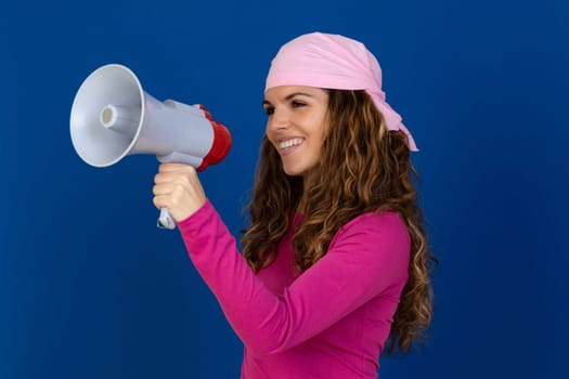 Hopeful woman wearing a pink scarf isolated on a blue background