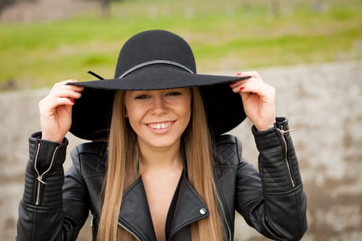 Stylish young woman with beautiful hat in the field