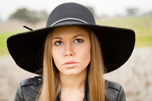 Stylish young woman with beautiful hat in the field