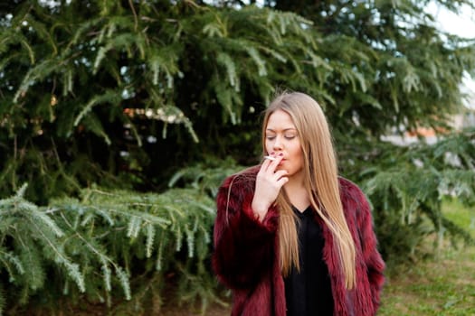 Pretty blond girl with long hair smoking in the park