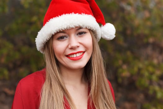 Young woman with Christmas hat and red lips in the forest