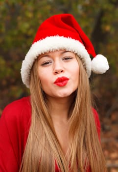 Young woman with Christmas hat and red lips in the forest