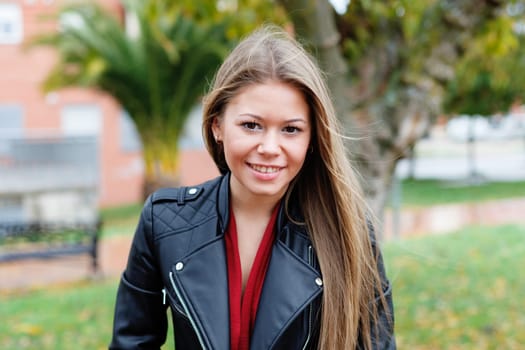 Blonde woman with leather jacket in a park