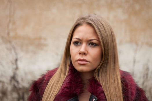 Melancholy young girl with red fur coat looking at side