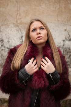 Melancholy young girl with red fur coat looking up