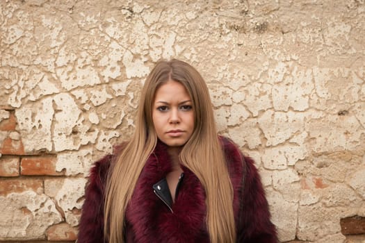 Melancholy young girl with red fur coat looking at camera