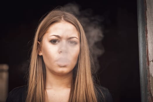 Attractive young blond girl smoking a cigar