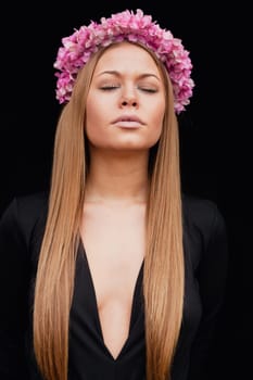 Beautiful portrait of a blonde girl with a pink crown of flowers on her head
