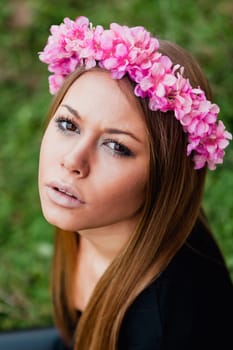 Beautiful portrait of a blonde girl with a pink crown of flowers on her head