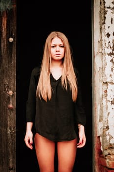 Sensual blonde girl in black shirt waiting near a wooden door