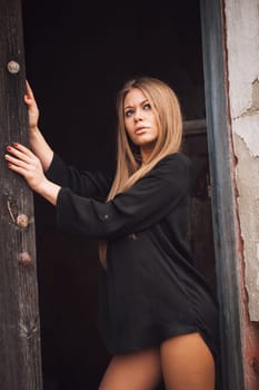 Sensual blonde girl in black shirt waiting near a wooden door