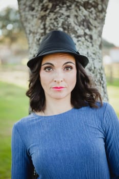 Stylish young woman with black hat in the field
