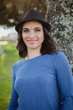 Stylish young woman with black hat in the field