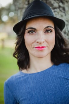 Stylish young woman with black hat in the field
