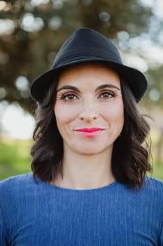 Stylish young woman with black hat in the field