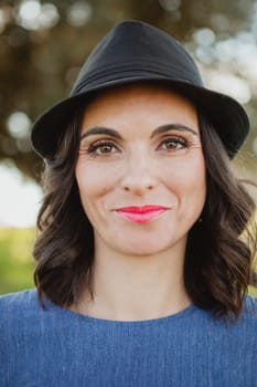 Stylish young woman with black hat in the field
