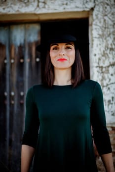 Pretty brunette girl in black with a stylish hat and a old wooden door of background