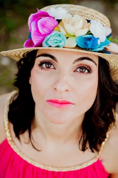 Stylish woman with a red dress and straw hat with flowers in the field