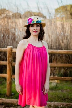 Stylish woman with a red dress and straw hat with flowers in the field