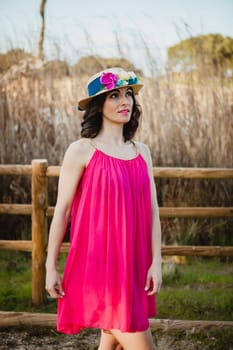 Stylish woman with a red dress and straw hat with flowers in the field