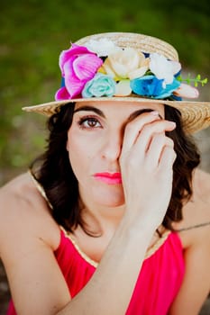 Stylish woman with a red dress and straw hat with flowers in the field