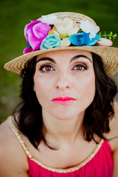 Stylish woman with a red dress and straw hat with flowers in the field