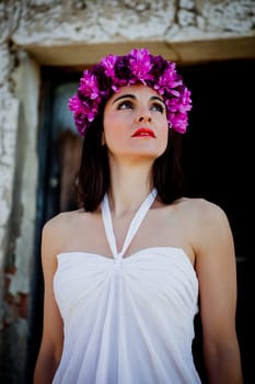 Beautiful Young Woman with Pink Flowers and White dress. Long Brunette Hair and Fashion Makeup