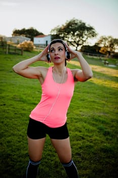 Beautiful girl outdoors enjoying nature in clothes for running with headphones