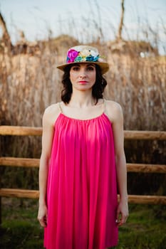 Stylish woman with a red dress and straw hat with flowers in the field