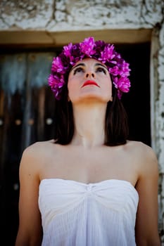 Beautiful Young Woman with Pink Flowers and White dress. Long Brunette Hair and Fashion Makeup